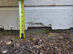 Photo showing damage to clapboard siding when it is installed too close to the dirt